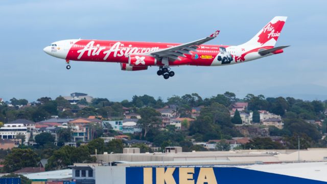 white and red Air Asia passenger plane above Ikea building during daytime